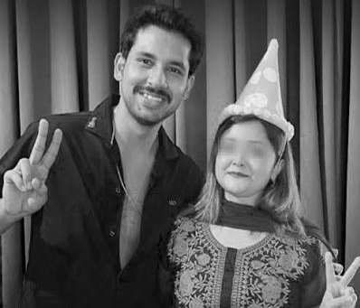 "A man and a woman wearing a birthday party hat smiling and showing peace signs in a black and white photo"